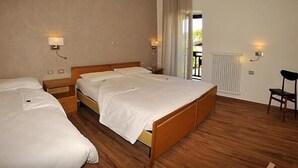Habitación de hotel con dos camas individuales, suelo de madera, un radiador y una silla.