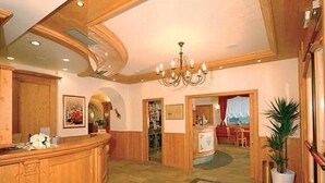 Un vestíbulo con un mostrador de recepción de madera, un candelabro y un área de comedor al fondo.