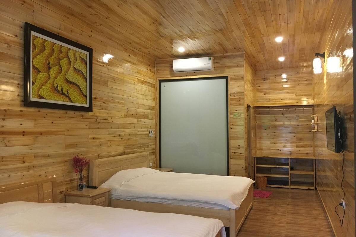 A wooden cabin room with two beds, a framed picture, an air conditioner, and a television.