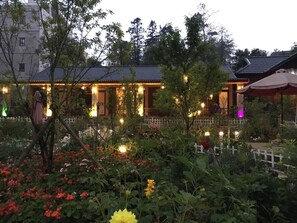 A traditional building with a tiled roof, surrounded by a garden with various plants and flowers. - Sapa Garden Resort (Sa Pa)