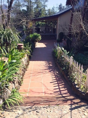 A pathway leading to a building surrounded by greenery and a white fence. - Sapa Garden Resort (Sa Pa)
