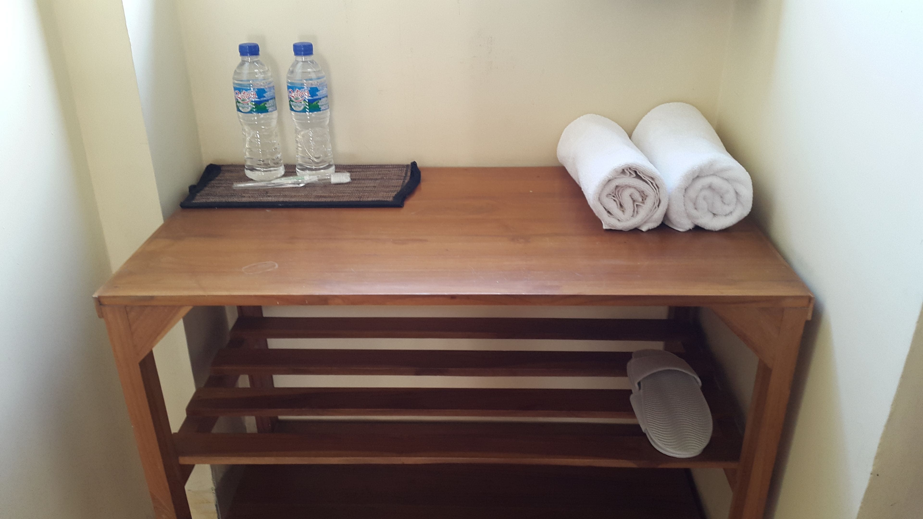 A wooden table with two bottles of water and two rolled towels.