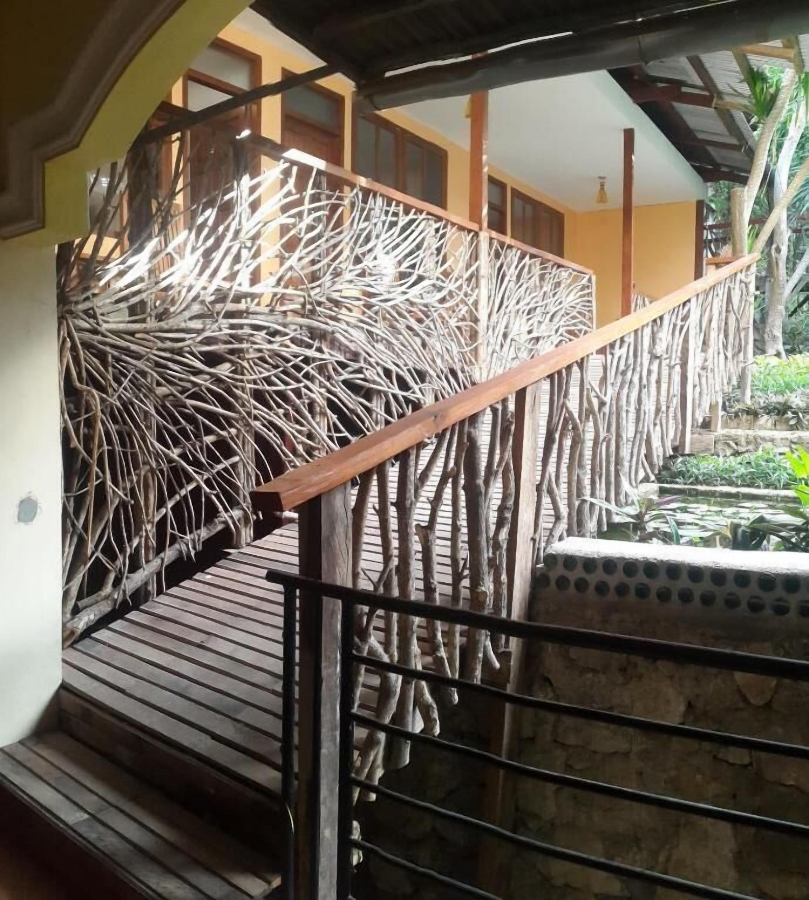Un escalier en bois doté d’une rampe au design original, réalisée à l’aide d’un motif tressé, menant à un niveau supérieur.
