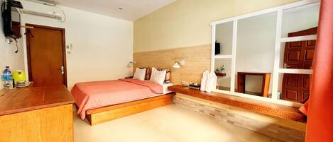 A bedroom with a bed, bedside table, and a window with a view of the outside.