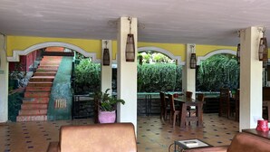 Ein Restaurant mit einer Treppe zu einem Garten, Außenplätzen und einem gefliesten Boden.