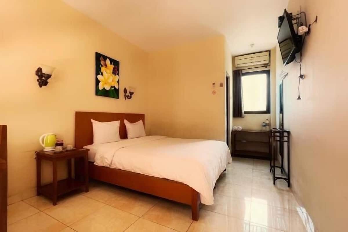 A bedroom with a bed, a nightstand, a chair, a desk, and a window.