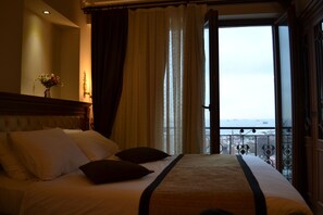 Habitación triple Deluxe, vistas al mar | Minibar, caja fuerte, escritorio y cortinas opacas