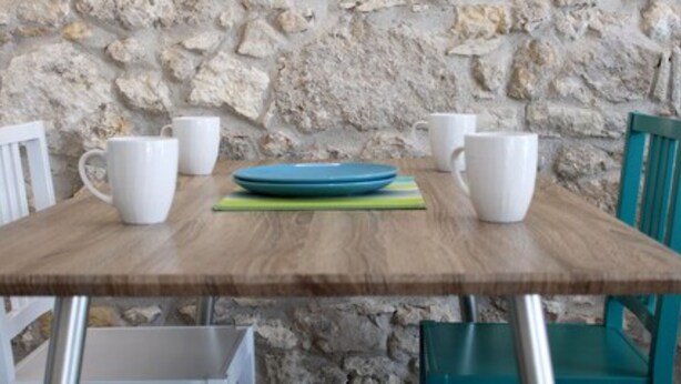 A wooden table with white and blue chairs, white mugs, and a blue plate. - Archinuè Suite & Apartments (Syracuse)