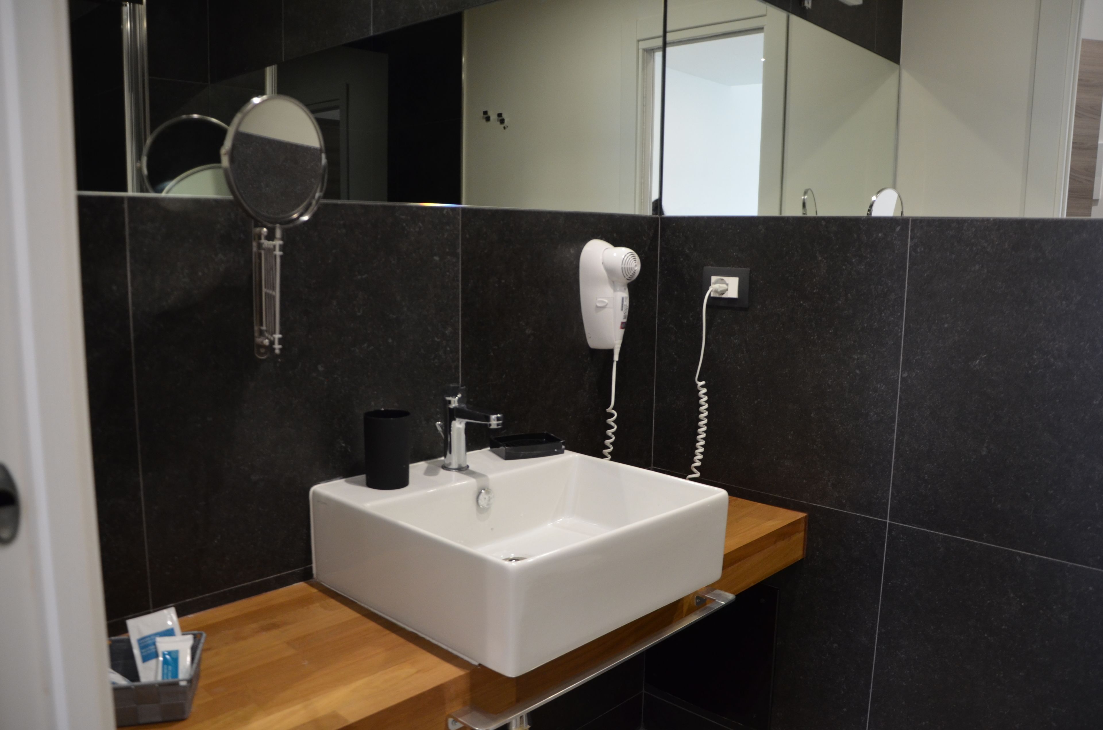 A modern bathroom with a white sink, a handheld hair dryer, and a mirror.