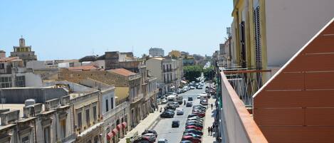Vista de la calle con coches aparcados, edificios y cielo despejado.