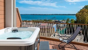A balcony with a hot tub, a lounge chair, and a view of the sea. - Archinuè Suite & Apartments (Syracuse)