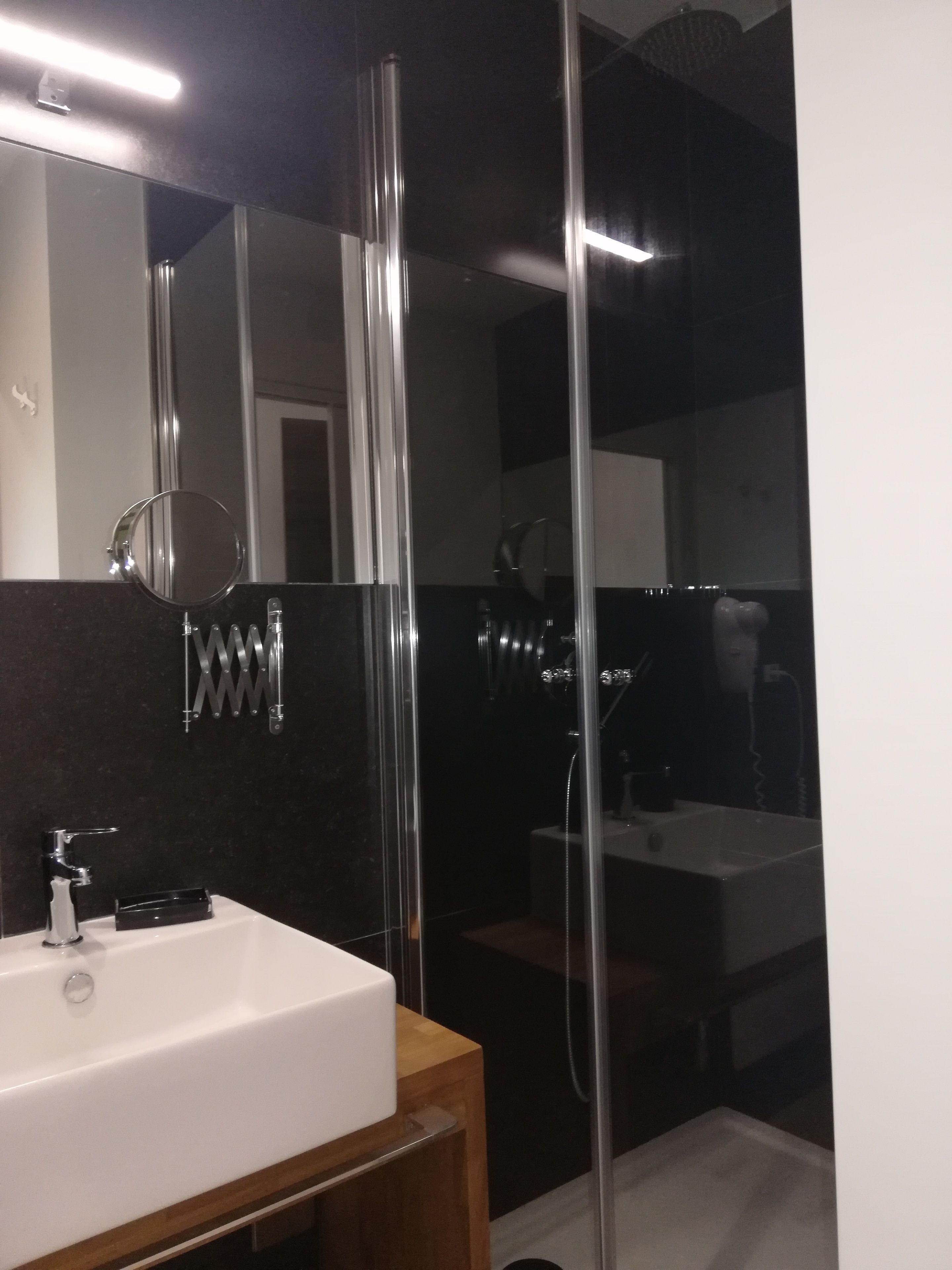 Ein modernes Badezimmer mit einem weißen Waschbecken, einem Spiegel und einer Duschkabine.