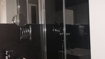 Ein modernes Badezimmer mit einem weißen Waschbecken, einem Spiegel und einer Duschkabine.