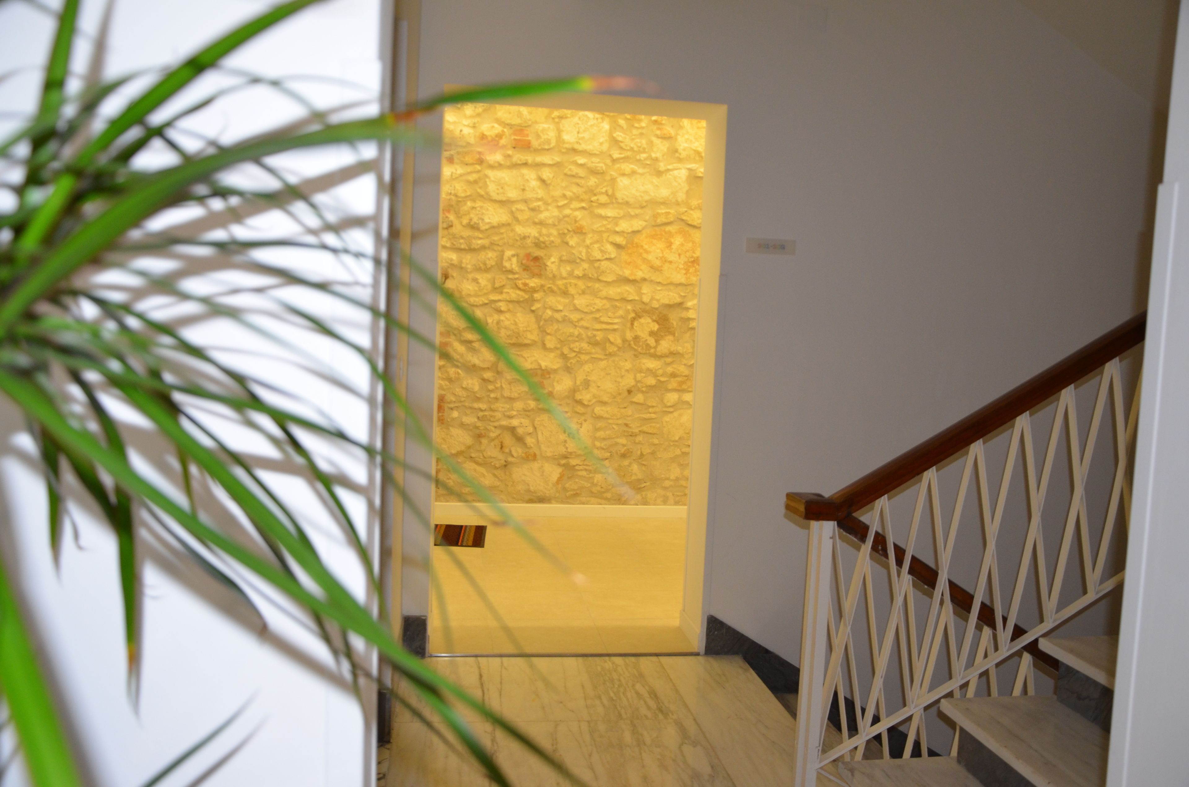 A staircase with a wooden handrail and a stone wall at the top.