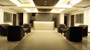 Ein Empfangsbereich mit einer Rezeption, zwei Sofas und einer Treppe im Hintergrund.