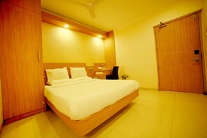 A hotel room with a large bed, wooden headboard, a bedside table with a lamp, and a wardrobe. - Horizon Heights Serviced Apartments (Coimbatore)