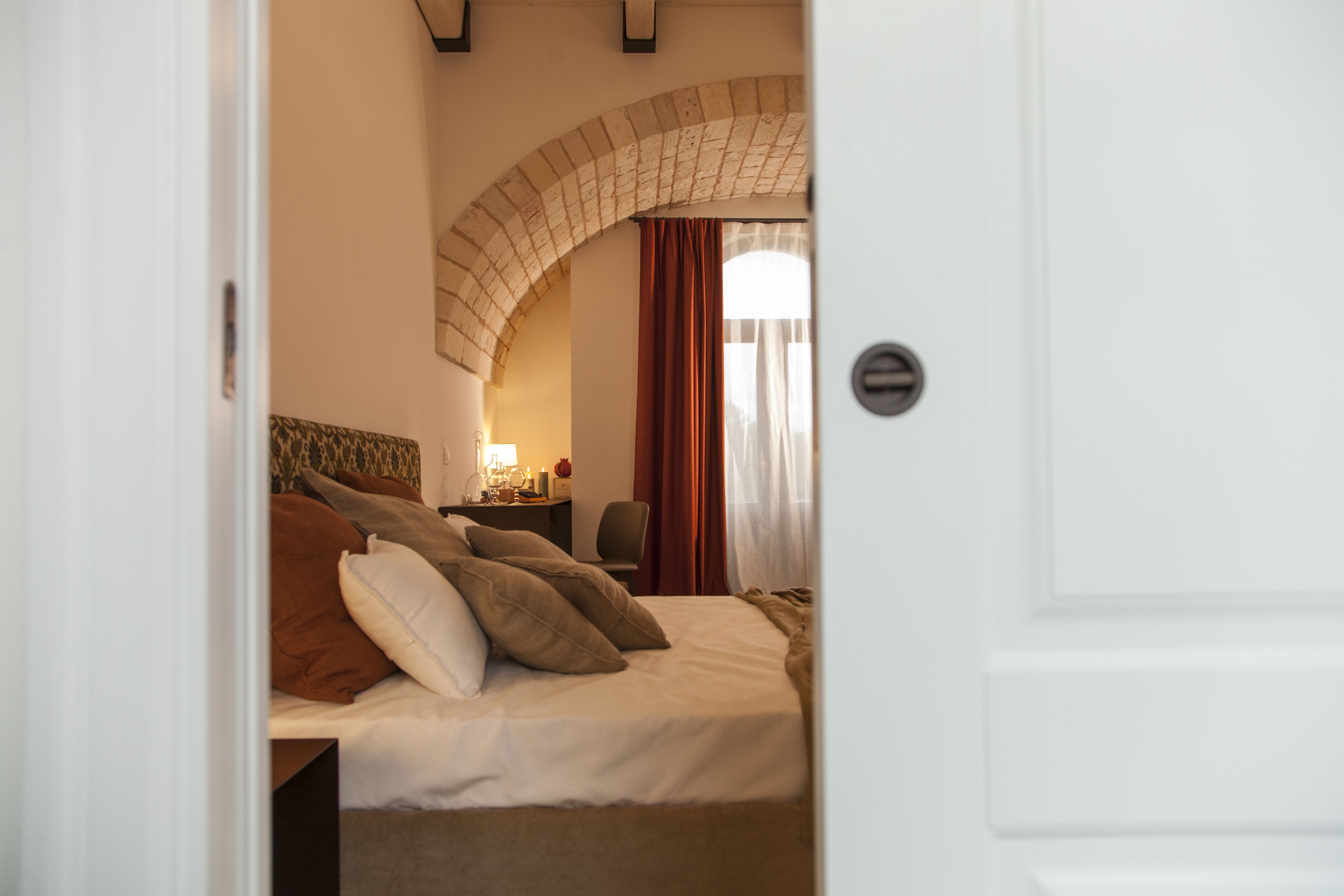 Una habitación de hotel con cama, escritorio con lámpara y ventana con cortinas.
