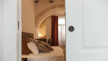 A hotel room with a bed, a desk with a lamp, and a window with curtains.