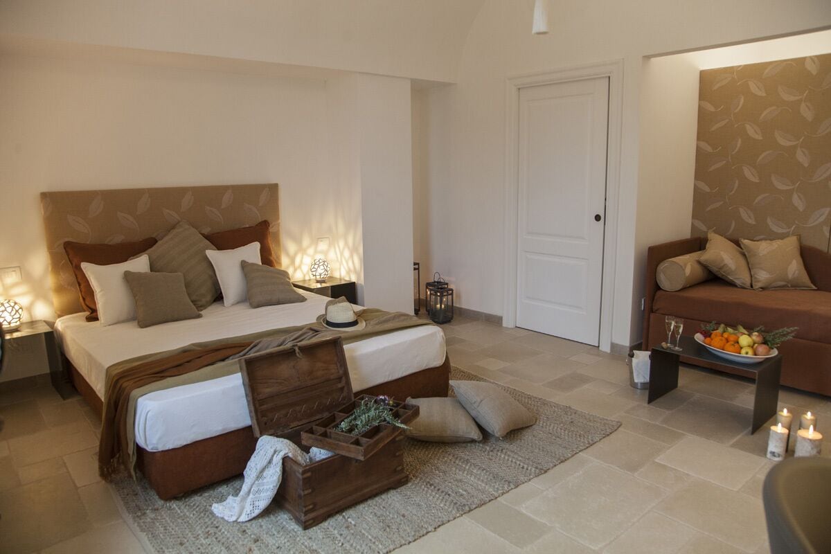 A bedroom with a bed, bedside tables, a dresser, a nightstand, a sofa, a coffee table, and a door.