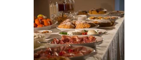 Une table de buffet proposant une variété d’aliments, notamment des pâtisseries, des fruits et des viandes.