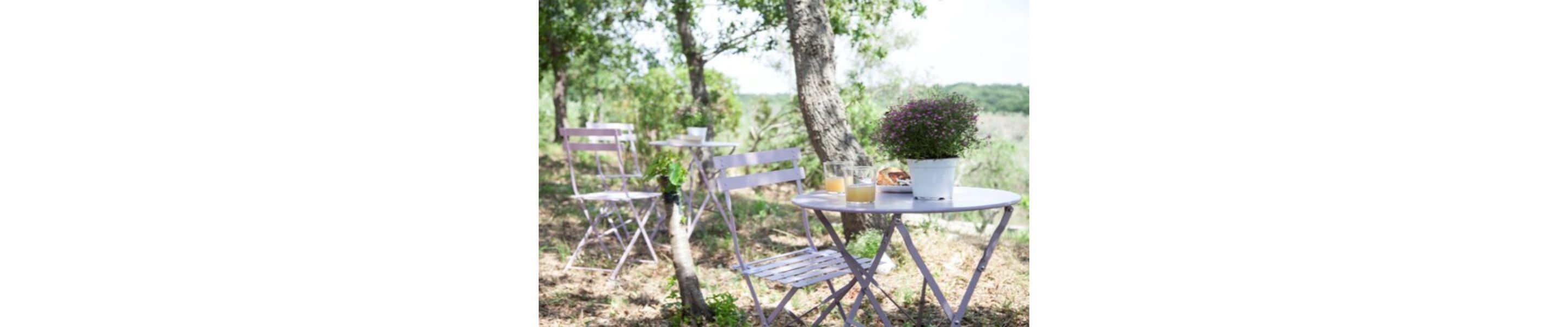 A round table with a potted plant, two glasses of orange juice, and a plate with a pastry.