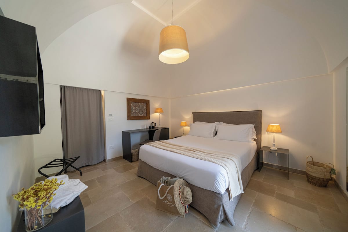 A modern hotel room with a large bed, bedside lamps, a desk, and a chair.