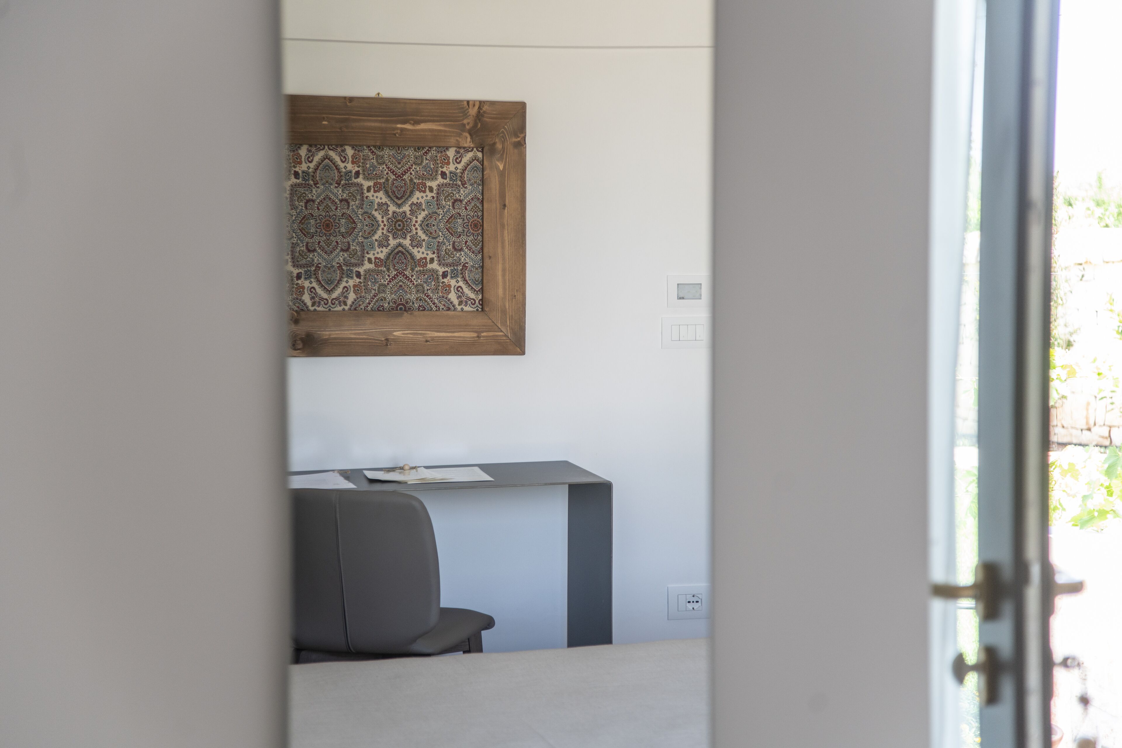 A room with a desk, chair, and a patterned wall hanging.
