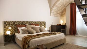 A bedroom with a large bed, a desk, and a staircase.