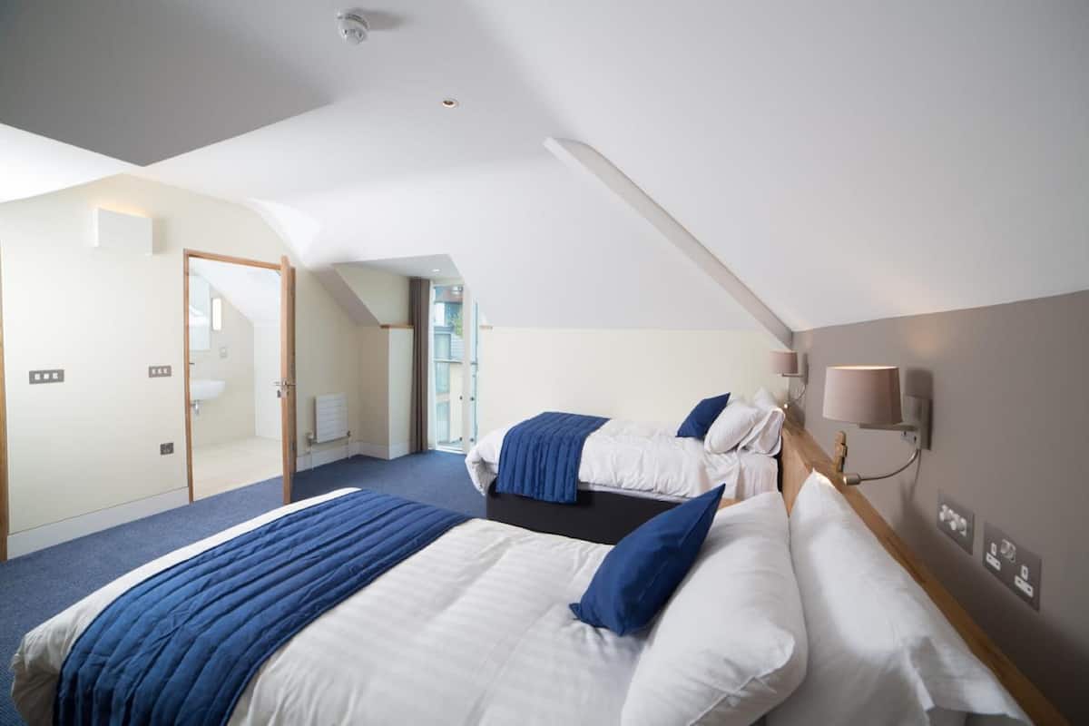 A hotel room with two beds, a bathroom, and a view of the outside.