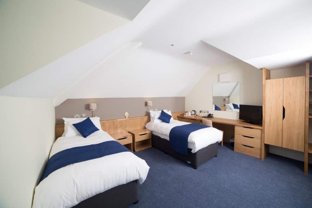 A hotel room with two beds, a desk, a TV, and a wardrobe.