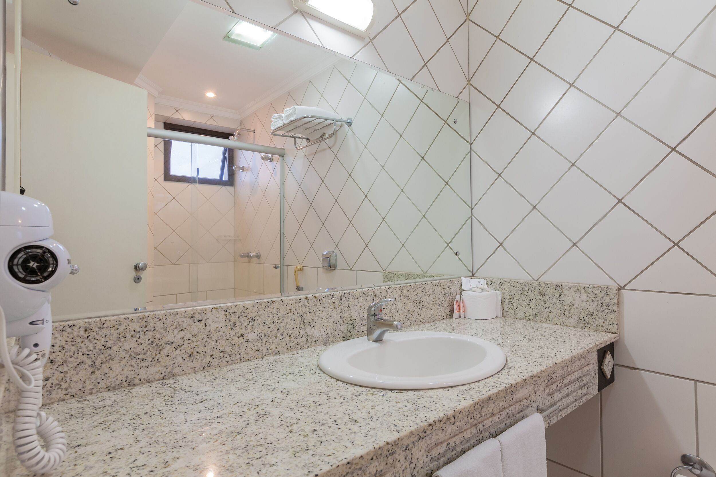 A bathroom with a granite countertop, a white sink, a towel rack, and a mirror.