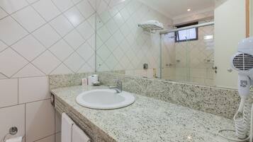 Baño con encimera de granito, lavamanos, espejo, toallero y secador de pelo.