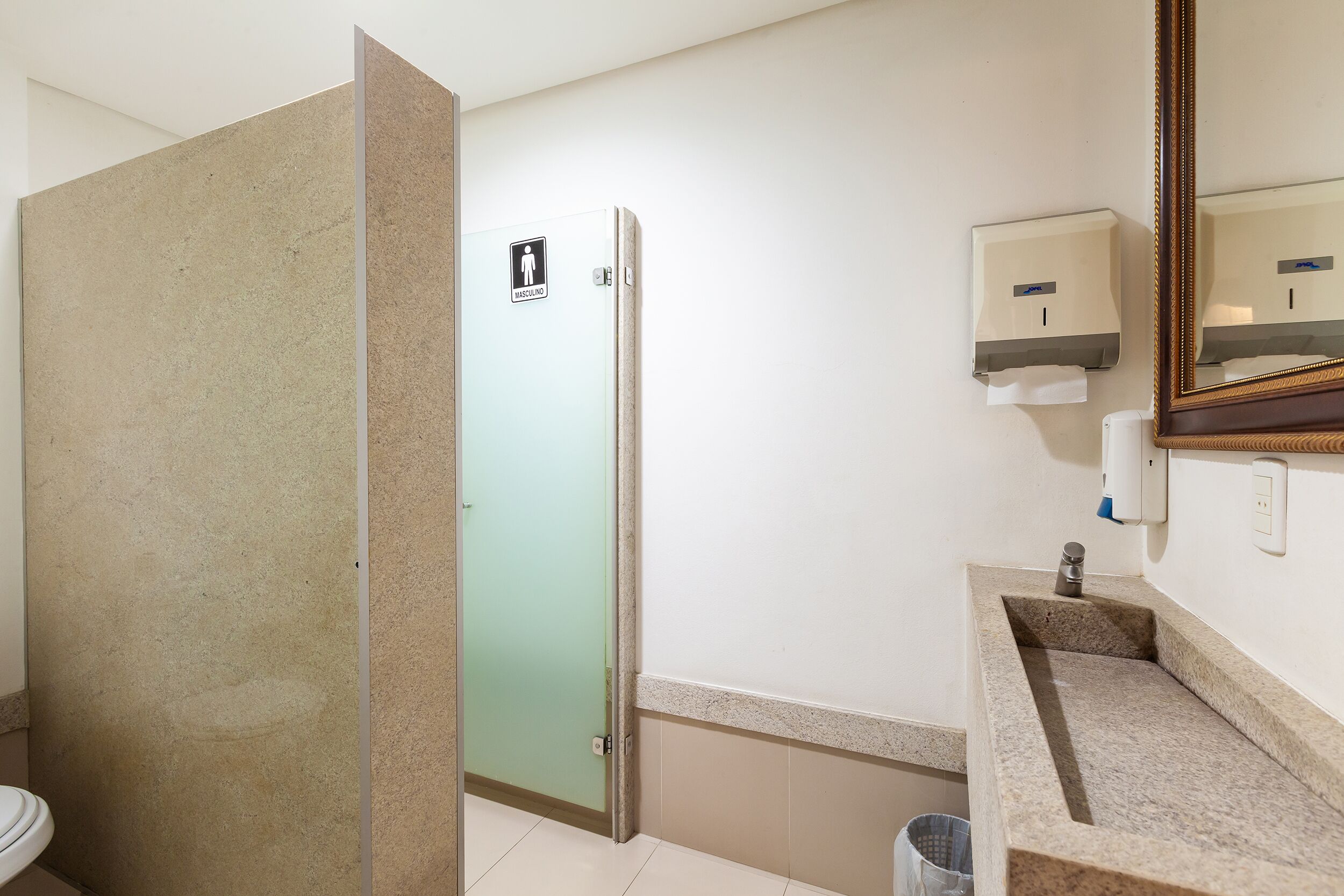A bathroom with a shower, toilet, sink, and hand dryer.