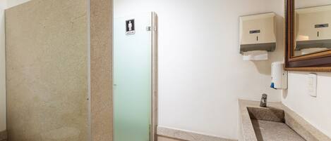A bathroom with a shower, toilet, sink, and hand dryer.