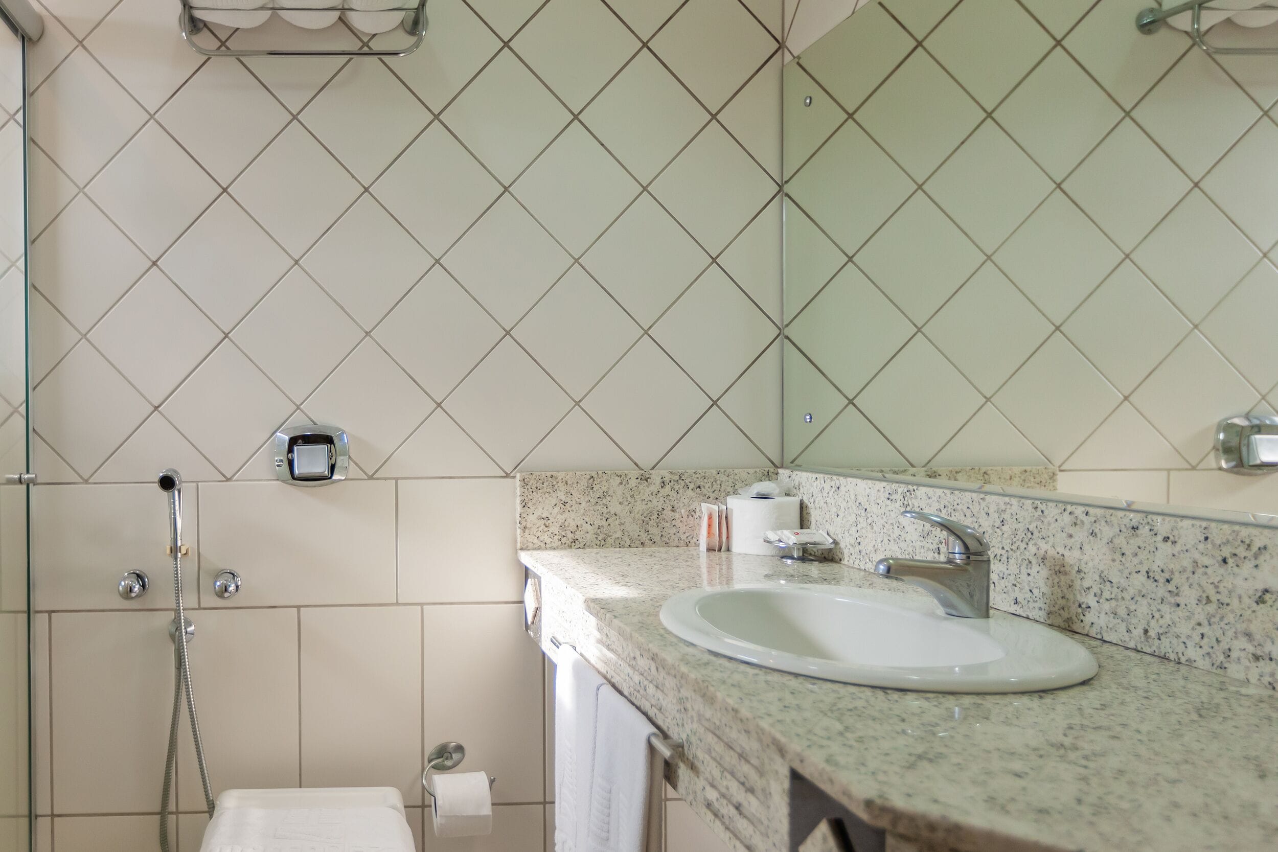 A bathroom with a sink, mirror, and shower.