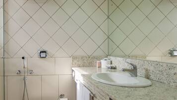 A bathroom with a sink, mirror, and shower.