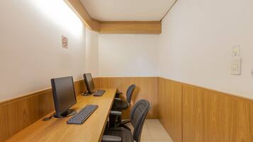 Una sala de conferencias con un escritorio de madera, dos monitores de computadora, un teclado y dos sillas de oficina.
