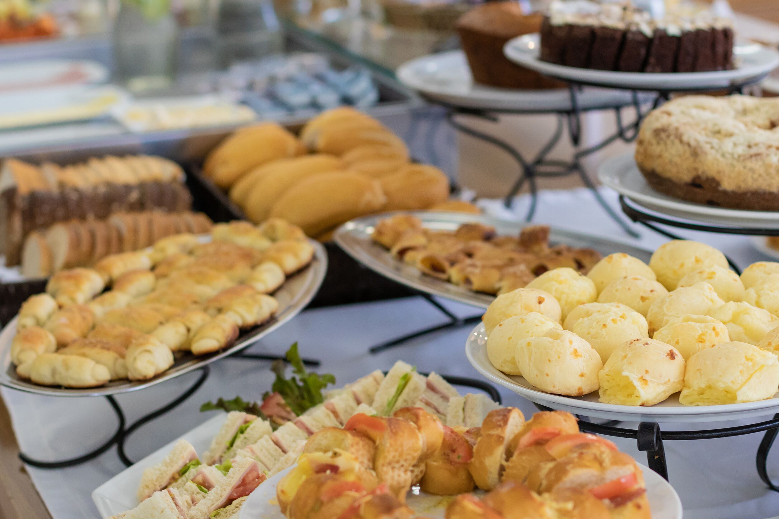 Un bufé con diversas opciones de comida, incluyendo sándwiches, pasteles y postres.