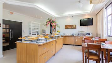 Una cocina moderna con barra libre, una zona de comedor con muebles de madera y un televisor montado en la pared.