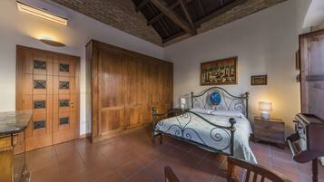 A bedroom with a bed, wooden wardrobe, and a painting on the wall.