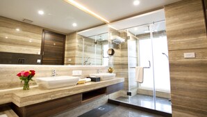 Een moderne badkamer met een grote spiegel, twee wastafels, een douche en een bloemenvaas.