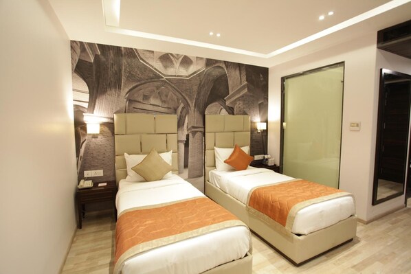 A hotel room with two beds, a large mural on the wall, and a glass door leading to a balcony. - Kaisons inn (New Delhi)