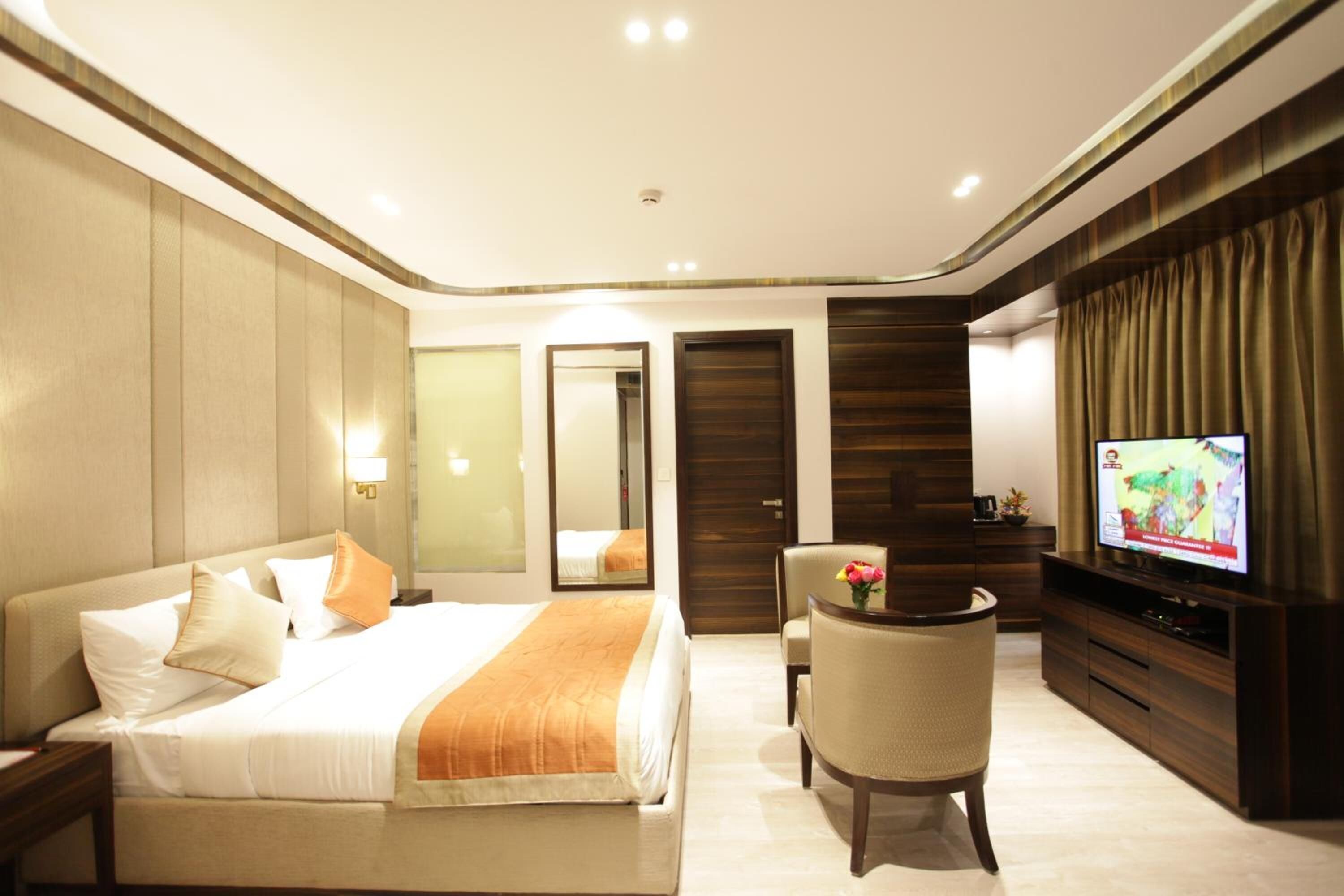 Una habitación de hotel con una cama, televisión, escritorio y una silla.