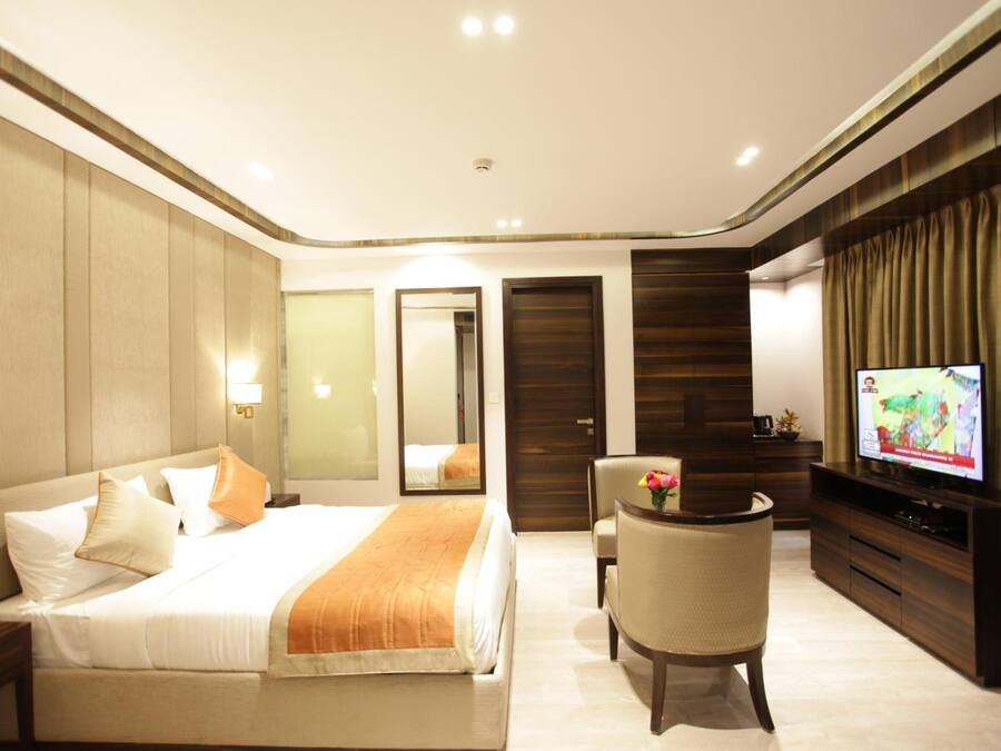 Una habitación de hotel con una cama, televisión, escritorio y una silla.