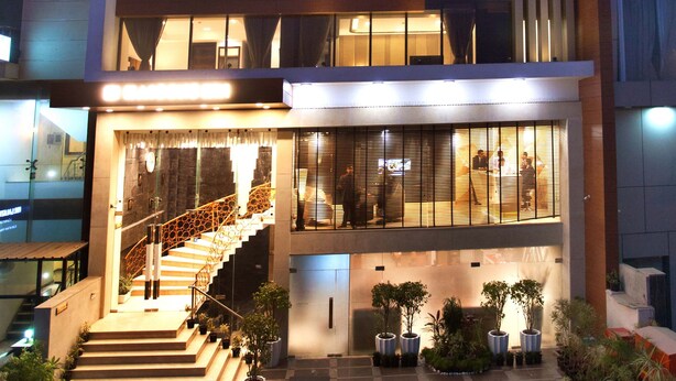 Een modern hotel met een opvallende ingang, een trap naar de lobby en een goed verlichte gevel.