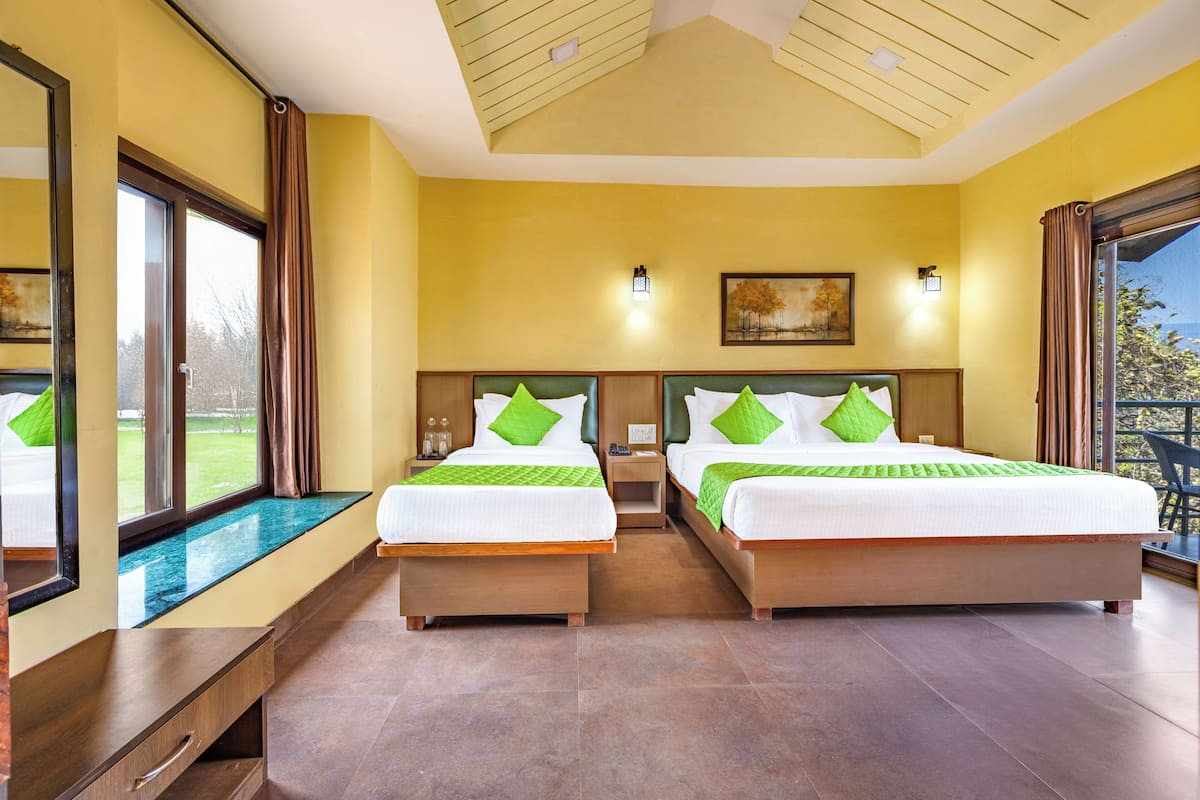 A hotel room with two beds, a large window, a ceiling with skylights, and a painting on the wall.