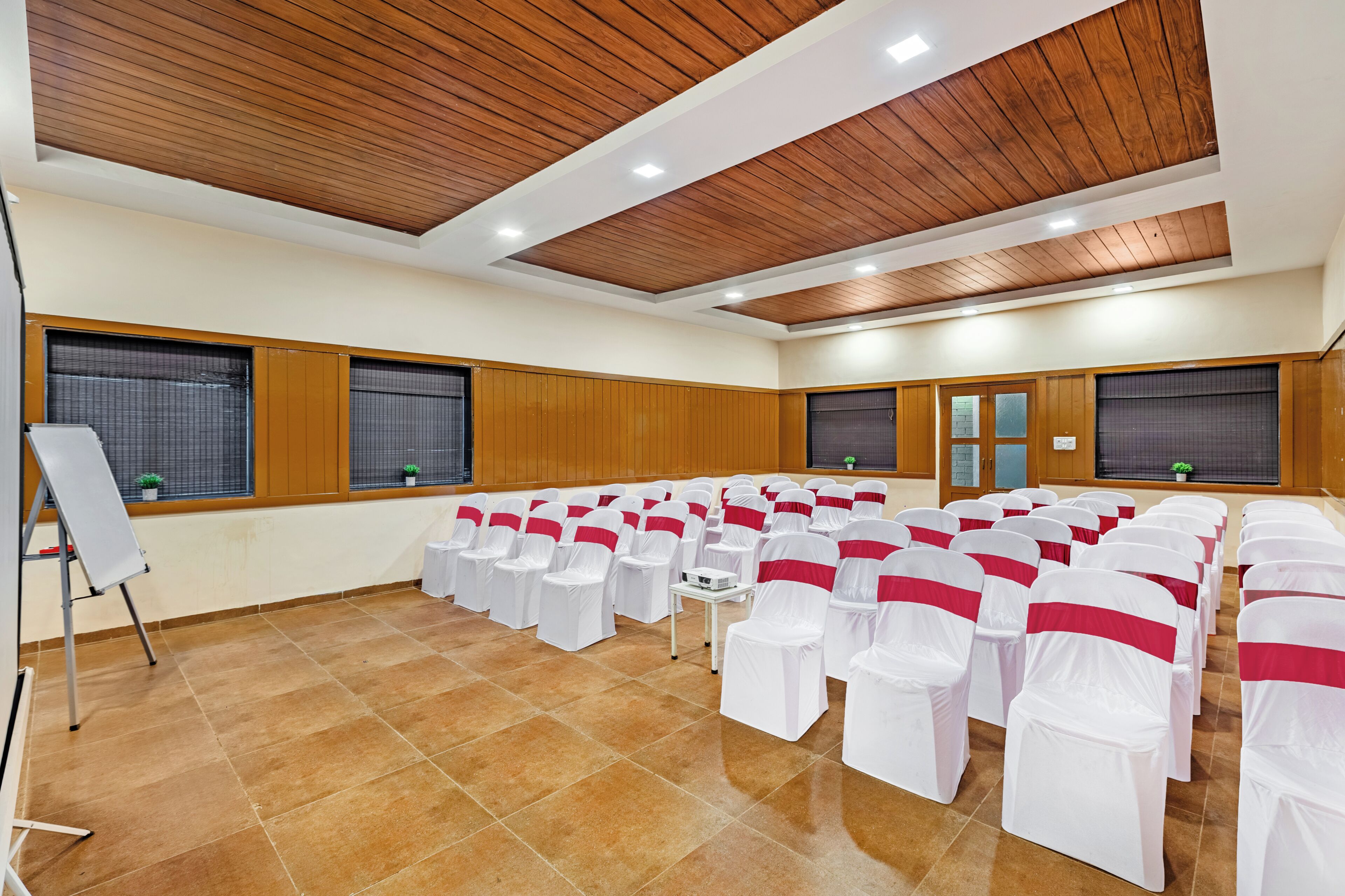 A conference room with rows of chairs, a whiteboard, and wooden paneling on the ceiling.