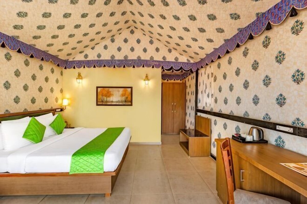 A hotel room with a bed, desk, and a door leading to a bathroom.
