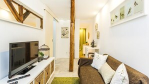 A modern living room with a television, a wooden beam, a desk, and a green rug. - Bairro Alto Green by Homing (Lisbon)
