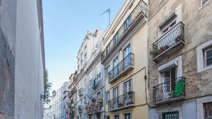 A narrow street lined with multi-story buildings, each with balconies and windows. - Bairro Alto Green by Homing (Lisbon)